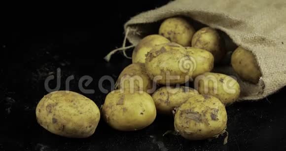 土豆放在帆布袋里的黑色冲浪板上一堆新鲜肮脏的生土豆视频的预览图