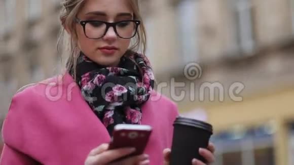 漂亮的女孩站在房子外面站在市中心喝杯咖啡发短信上网视频的预览图