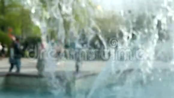 城市喷泉喷水在模糊的背景上人们在市中心的喷泉周围走来走去视频的预览图