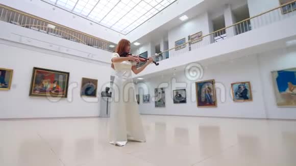 穿白色连衣裙的女士在画廊拉小提琴视频的预览图