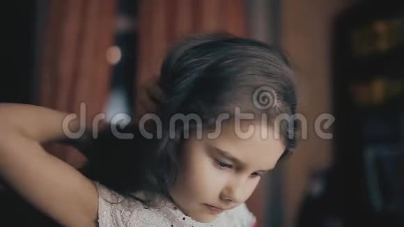 小女孩晚上在室内的房间里梳头微笑的小女孩梳头的肖像视频的预览图