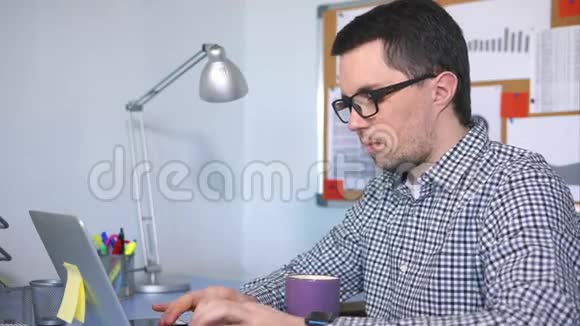 男性电脑用户在键盘上打字看着屏幕喝着咖啡视频的预览图