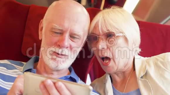 使用智能手机的高速国际列车的高级夫妇退休后积极的现代生活视频的预览图