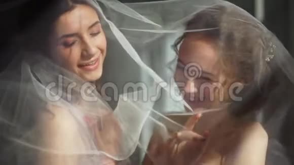 两个新娘在一个美丽的侧面灯光下玩面纱视频的预览图
