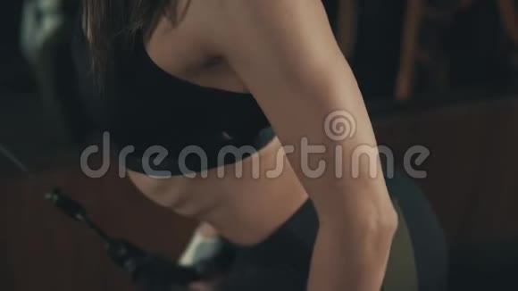在黑暗健身房用举重训练机进行漂亮的女子训练视频的预览图