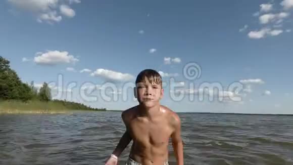 快乐的小男孩在水里溅起水花在湖里玩的孩子视频的预览图