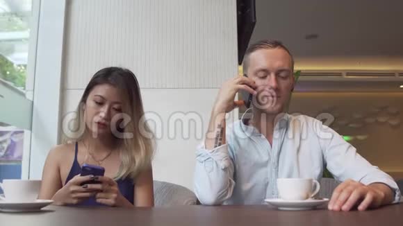 亚洲女人用电话和高加索男人说智能手机视频的预览图