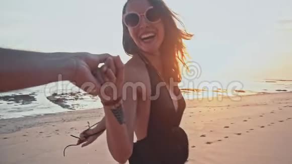 快乐的白种人夫妇在一起散步在空海滩日落时牵手海上暑假视频的预览图