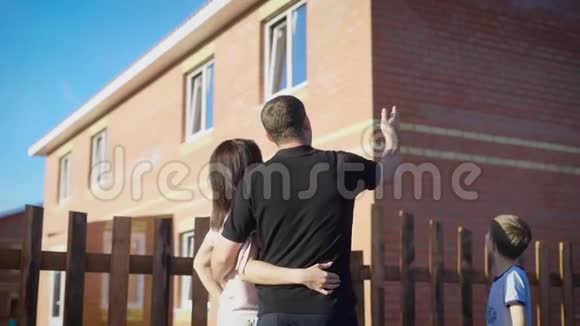 幸福的一对夫妇站在外面拥抱看着新的围栏公寓爱的家人在夏日阳光明媚的日子里视频的预览图