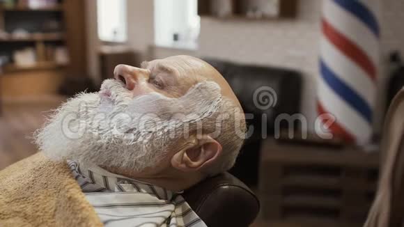 理发师用热毛巾遮住成熟男人的脸视频的预览图