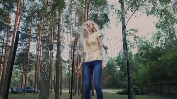 快乐的女性在蹦床上跳跃年轻漂亮的金发赤脚女人穿着浅色的夏季衬衫和牛仔裤视频的预览图