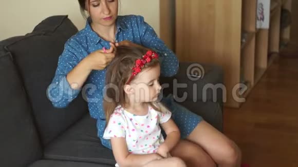 妈妈把女儿的头发扎成辫子一个幸福的家庭母亲节妇女节视频的预览图