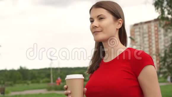 女人在公园里散步喝咖啡放松暑假微笑面对背景房子视频的预览图