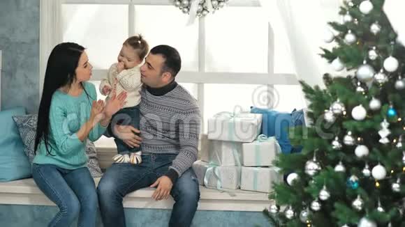 幸福的家庭坐在装饰有圣诞饰品的窗台上视频的预览图