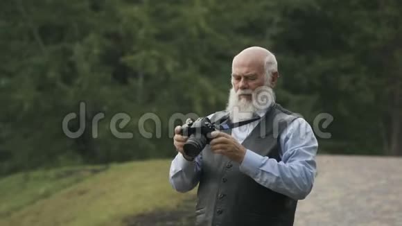 一位白发苍苍的老人为一个秋天的公园拍照视频的预览图