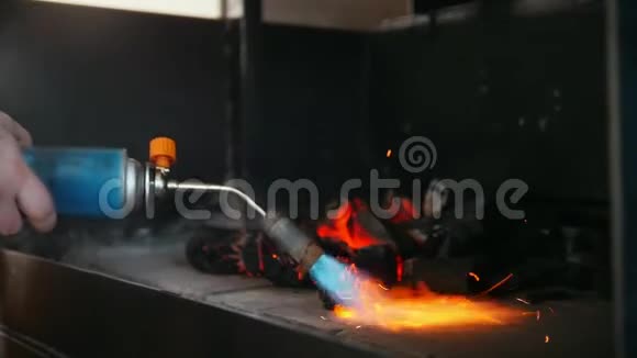 在烧烤炉中使用煤气燃烧器点燃木炭视频的预览图