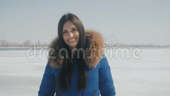 年轻美丽的黑发女子在冬天白雪皑皑的背景下微笑的肖像视频的预览图