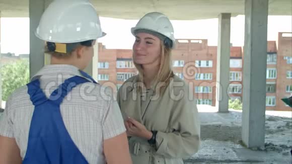 露天建筑工地的年轻建筑工人和女工谈话视频的预览图