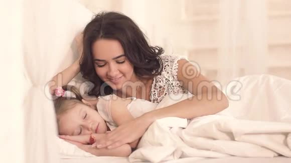 在睡着之前有爱心的母亲亲吻她熟睡的可爱的女儿视频的预览图