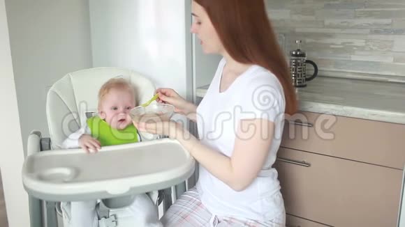 妈妈把婴儿奶酪放在一把高椅子上用一个鹳的器具视频的预览图