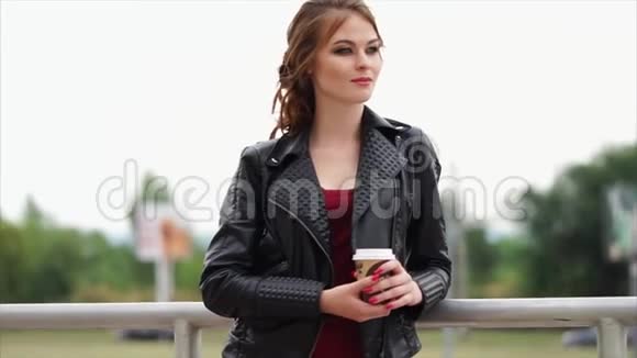 一个年轻的女人一头红发手里拿着一杯外卖的咖啡凝视着远方视频的预览图