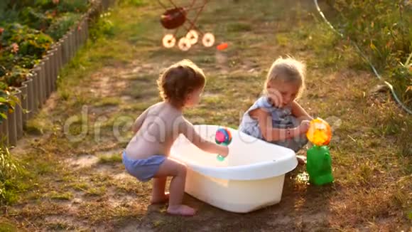 快乐开朗的孩子在暑假玩水可爱可爱的微笑的孩子们在花园里喷洒视频的预览图