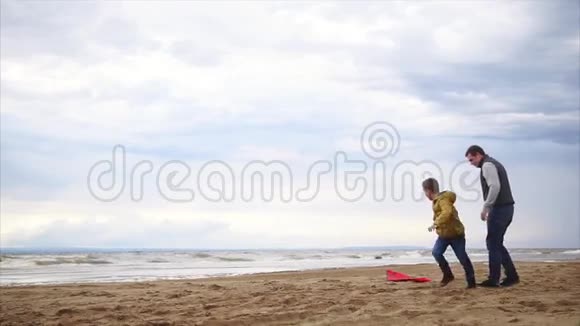家庭幸福孩子和他父亲在海滩上玩男孩放风筝视频的预览图