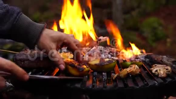 人手小心地从森林营火焰火烧烤盘中取出炒熟的蔬菜胡椒蘑菇视频的预览图