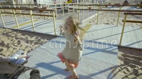一个金发小女孩欢快地跳在斯洛文尼亚的一个海岸上的操场上视频的预览图