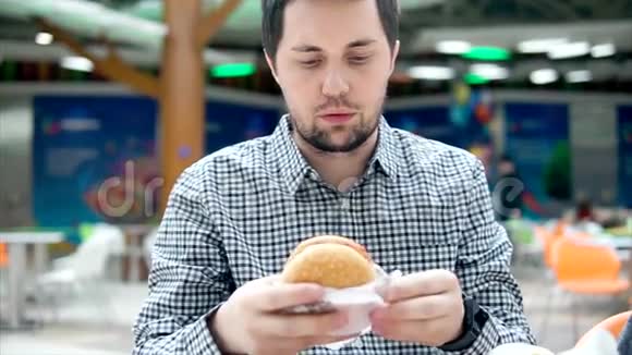 一个年轻人正在食物场吃一个带肉的汉堡包视频的预览图