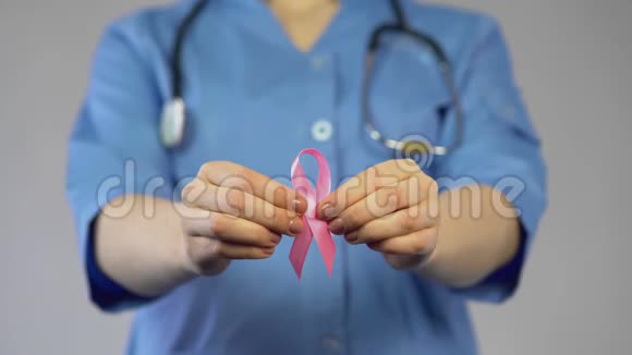 穿着蓝色外套的女性手中拿着粉红色的丝带并警告乳腺癌视频的预览图