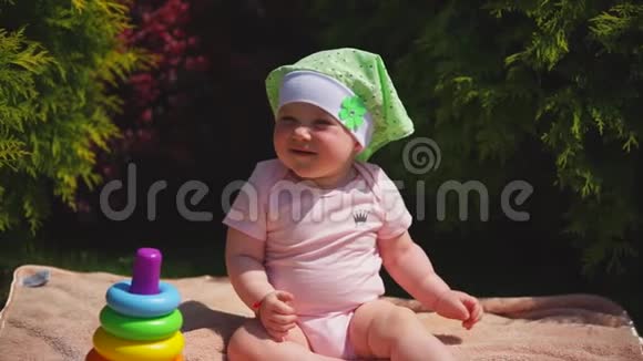 一个快乐的新生儿坐在公园的毛巾上接下来是一个玩具金字塔视频的预览图