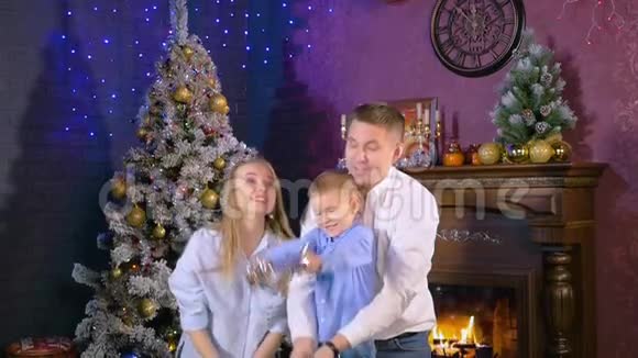 年轻快乐的家庭母亲父亲和儿子在圣诞壁炉里玩得很开心视频的预览图