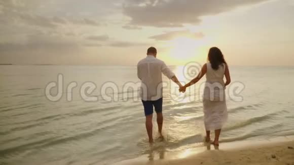 浪漫的情侣在日落时在海边散步蜜月和海边度假的概念视频的预览图