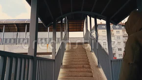 一个穿着米色外套的男人走上人行桥的楼梯视频的预览图