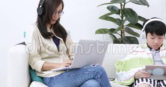戴眼镜的女人坐在沙发上在家里使用笔记本电脑在生活背景下工作室内视频的预览图