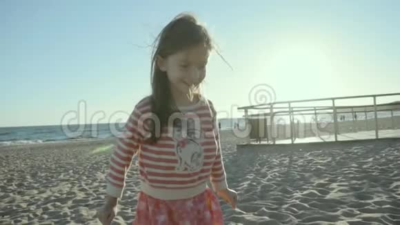 微笑着的小女孩站着跑着在海上海滩上跳跃日落时分在懒洋洋地视频的预览图