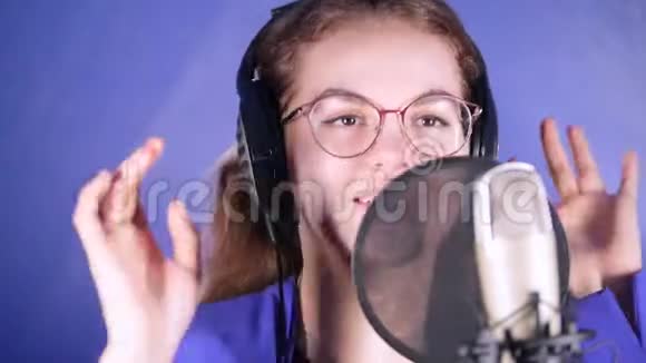 一位戴着耳机的年轻微笑女子在录音室唱歌视频的预览图