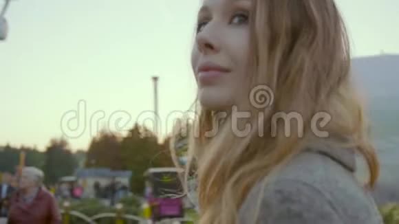 美丽的女孩穿着时尚的粉彩外套沿着景点公园散步视频的预览图