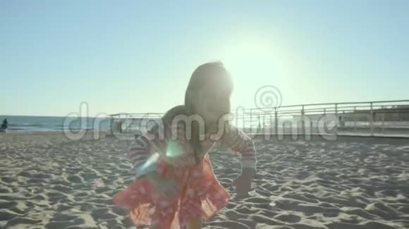 笑着的小女孩一边跑在海边一边跌跌撞撞地钻进沙里视频的预览图