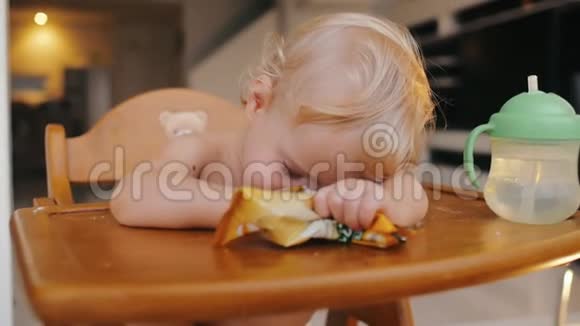 疲倦的孩子睡在高椅子上婴儿在美味的喂养后视频的预览图