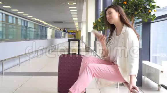 白种人年轻女性的肖像一个等待她的飞机通过智能手机通话的机场视频的预览图