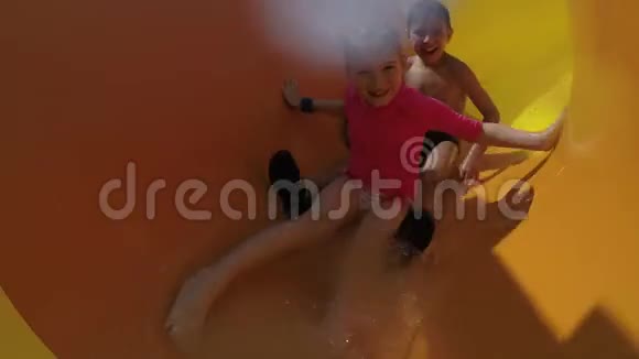 有趣的男孩和女孩滚着黄色的滑梯视频的预览图