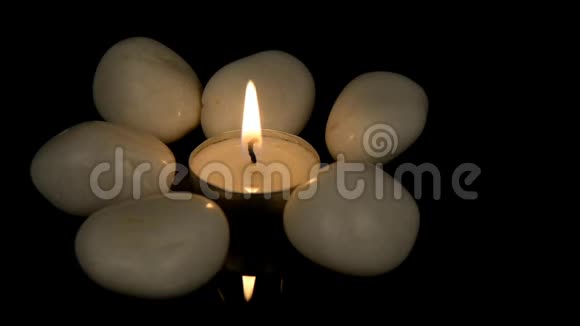 一支燃烧的蜡烛被白色的鹅卵石包围着视频的预览图