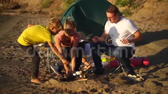 夏天一家人把棉花糖烧在帐篷附近的烤串上视频的预览图