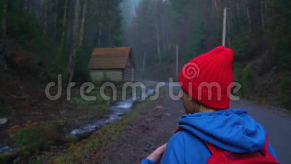 女旅行者背着背包在河边的山路上行走欣赏周围的风景视频的预览图