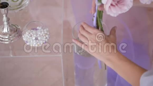 透明桌子背景上花瓶里的美丽花朵视频的预览图