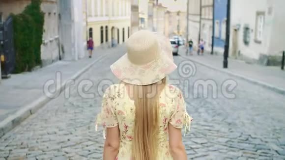 微笑的女人走在街上穿着白色帽子的开朗漂亮的女人在城里散步时回头看相机视频的预览图