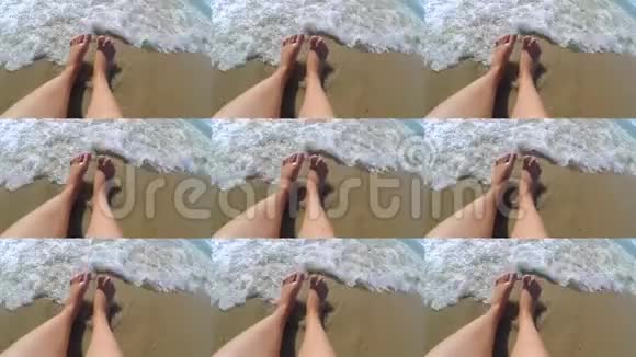 这个女孩坐在海边早上她的脚被海浪卷起来视频的预览图