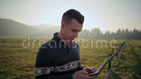 帅哥在日落时使用智能手机户外在大自然中使用LenseFlare视频的预览图
